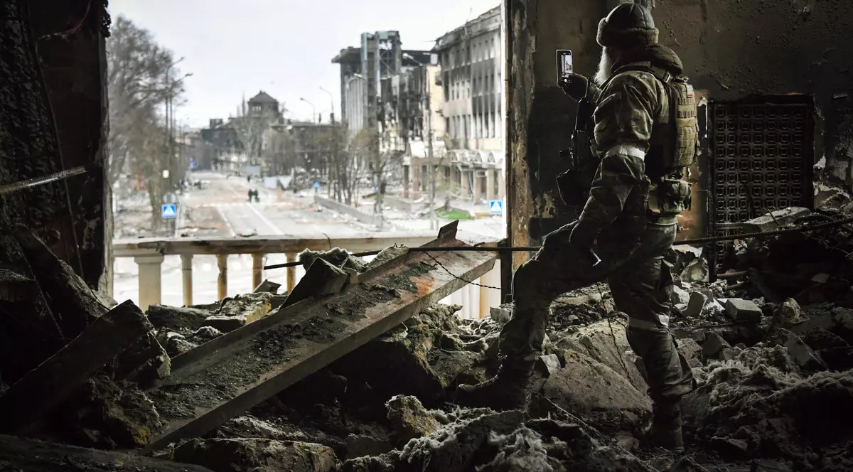 Un soldat rus patrulează in teatrul dramatic din Mariupol, bombardat pe 16 martie, pe 12 aprilie 2022. Foto: AFP
