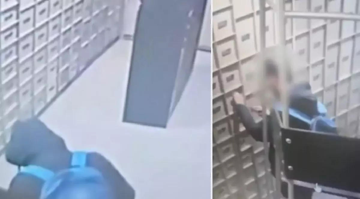 O cameră de supraveghere surprinde o persoană îmbrăcată cu o haină neagră și purtând un rucsac albastru în interiorul unei camere cu rafturi metalice.