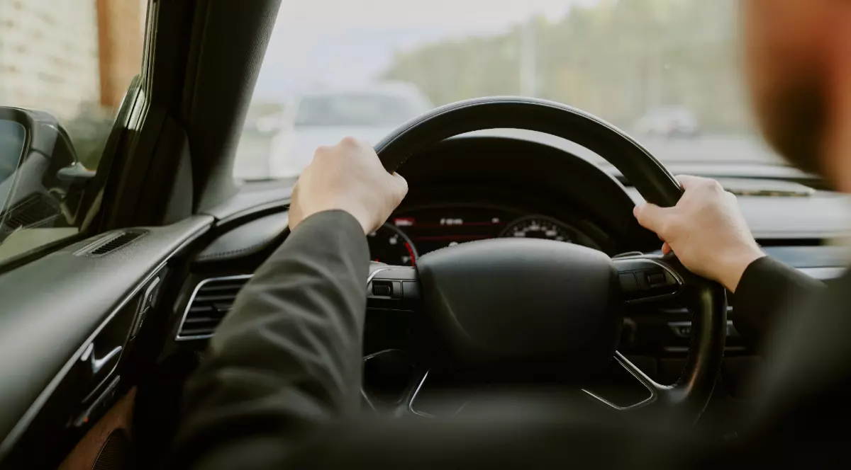 Un tânăr care ține mâinile pe volan