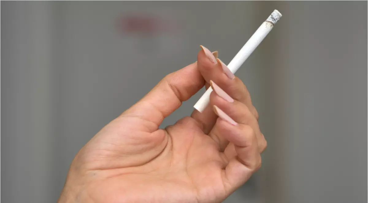 O fată care ține în mână o țigară.