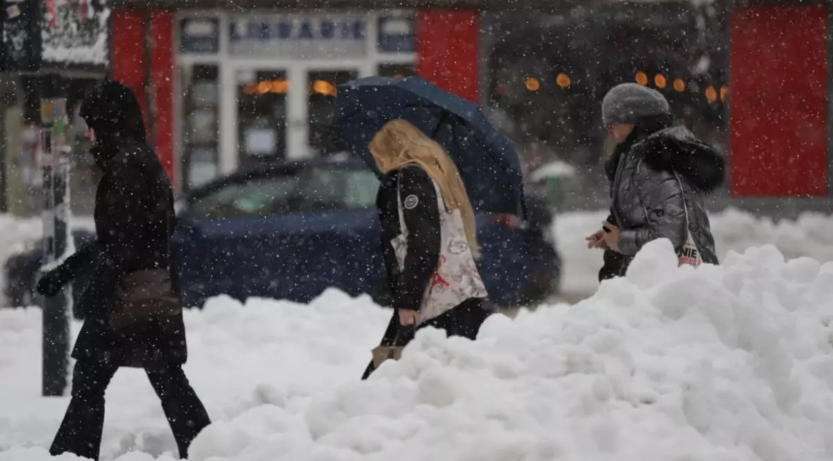 Mai mulți oameni merg pe stradă, în București, sunt nămeți de zăpadă și ninge, 18 februarie 2026