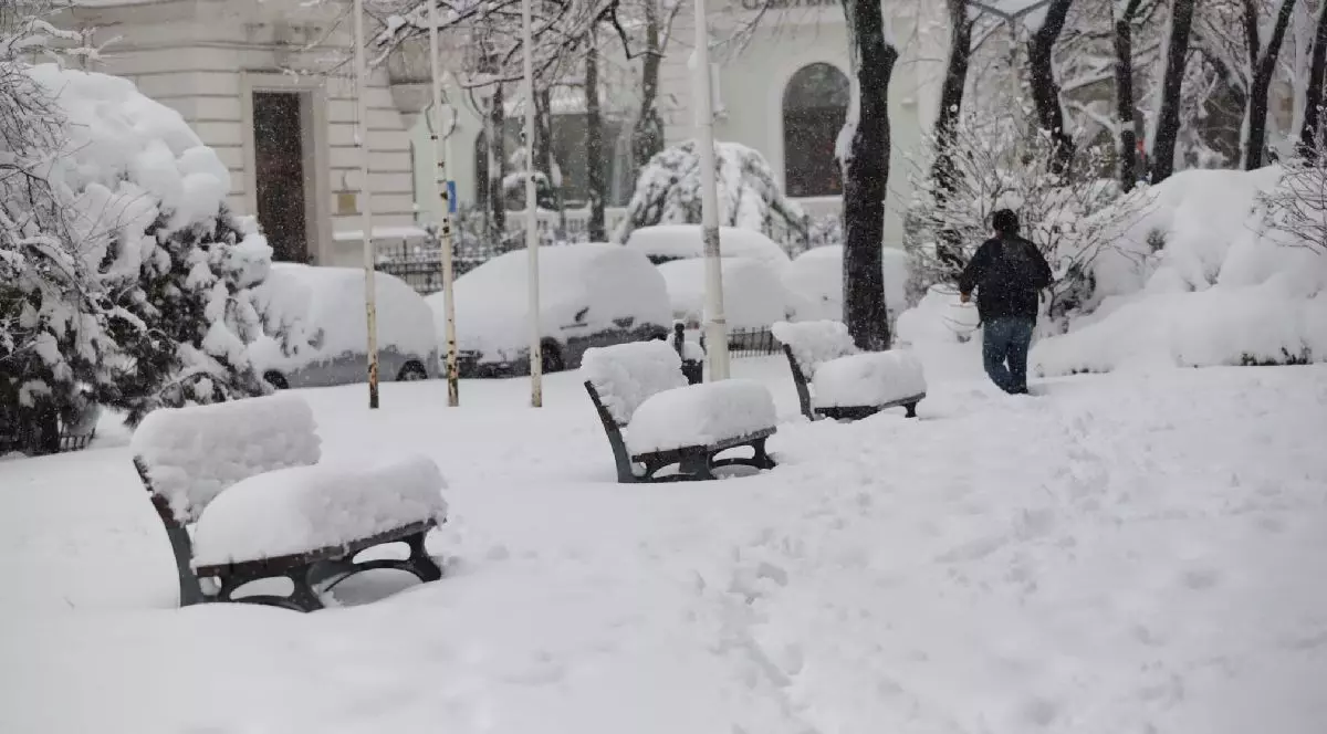 Zapada pe banci, pe strada, pe masini si un om mergand prin zapada. Ninsoare pentru creier, zapada ocihi. Foto Dumitru Angelescu Libertatea
