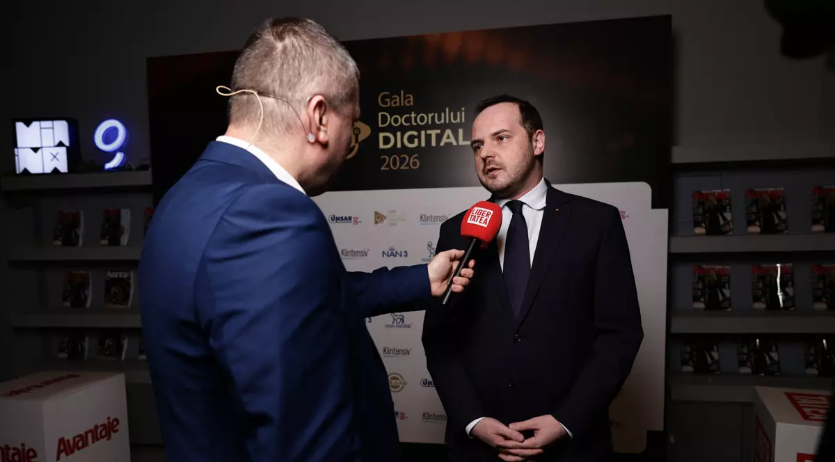 Dorin Chioțea, îmbrăcat în costum albastru închis și Alexandru Rogobete în timp ce oferă un interviu.