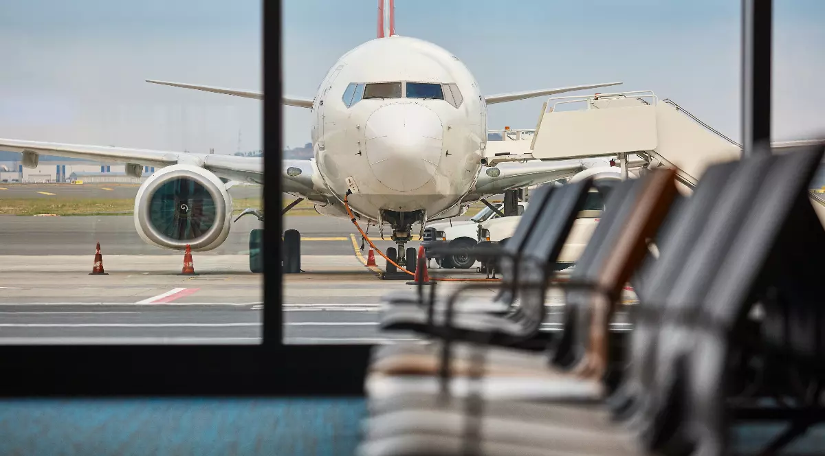 Un avion fotografiat din interiorul unui aeroport, pe pistă.