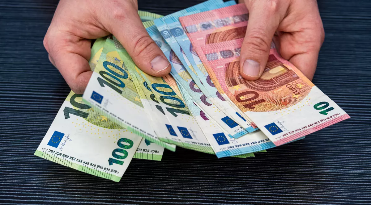 Un bărbat care ține bancnote de euro în mână.