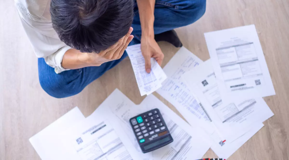 Un bărbat care citește facturile la gaze și la energie, calculează prețul și își pune mâna în cap