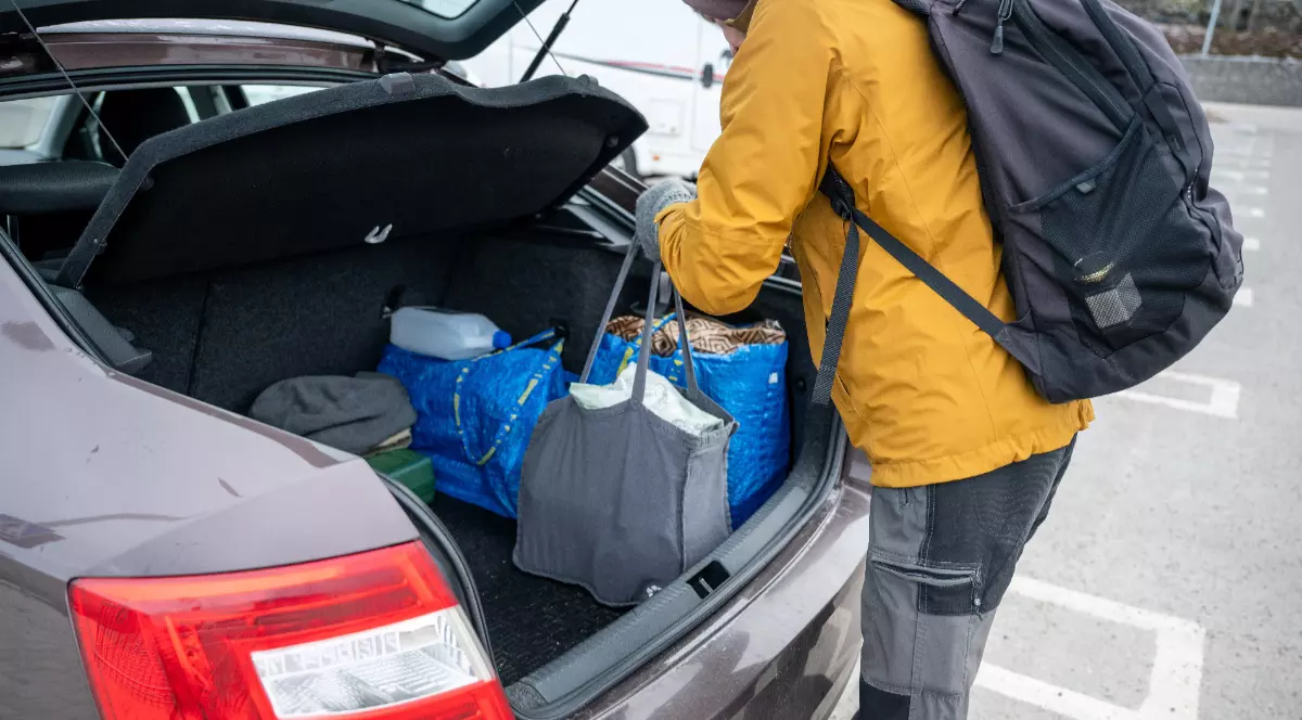 Un bărbat care își pune cumpărăturile în mașina, în mai multe plase
