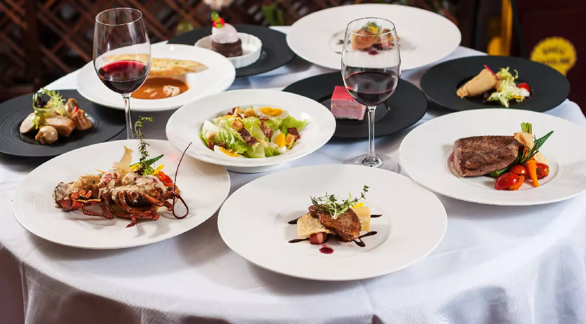 Mai multe feluri de mâncare și pahare de vin pe o masă dintr-un restaurant din Franța