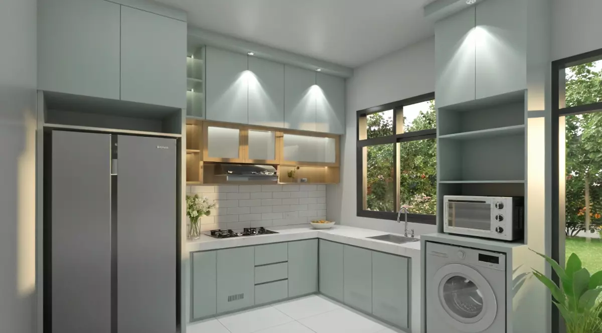 Imaginea prezintă o bucătărie modernă, luminoasă, amenajată în formă de L, cu mobilier în nuanțe deschise și iluminare ambientală discretă. În spațiu se observă un frigider mare, o mașină de spălat rufe, un cuptor cu microunde și o plită încorporată, toate integrate armonios în designul contemporan.