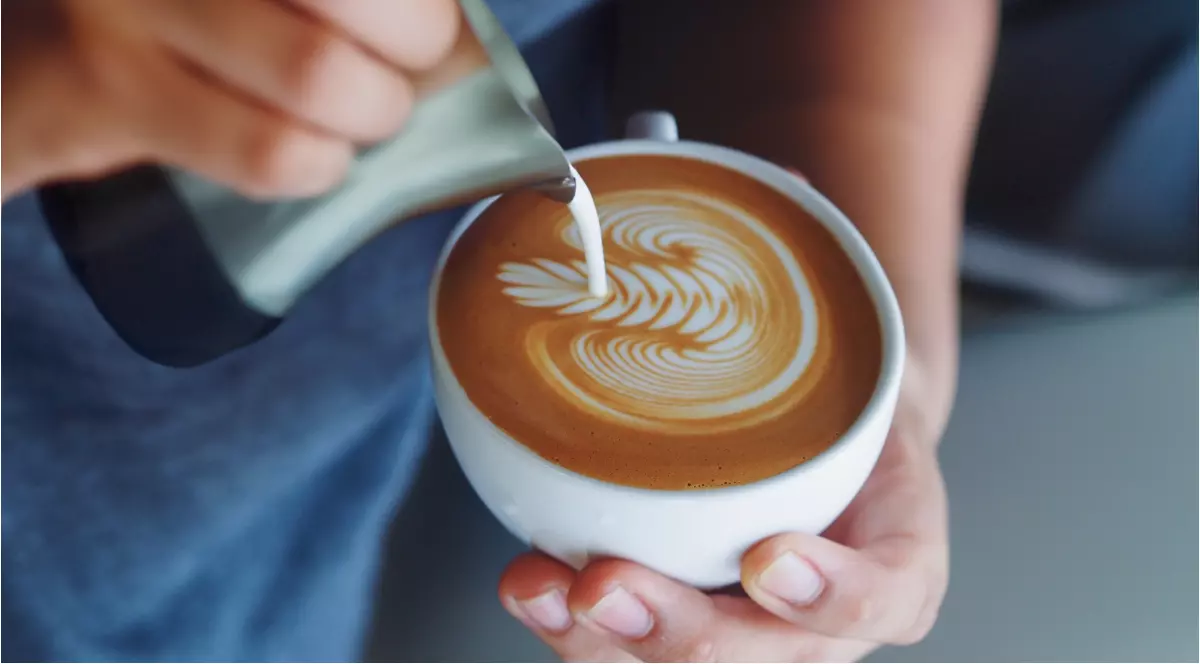 O persoană care prepară o cafea într-o ceașcă albă.