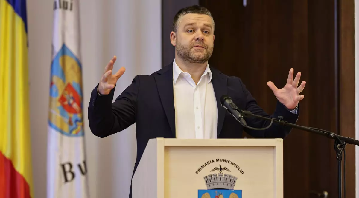 Ciprian Ciucu, cu mâinile întinse, îmbrăcat în sacou negru și cămașă albă, la o conferinta de presă pe 26 martie 2026