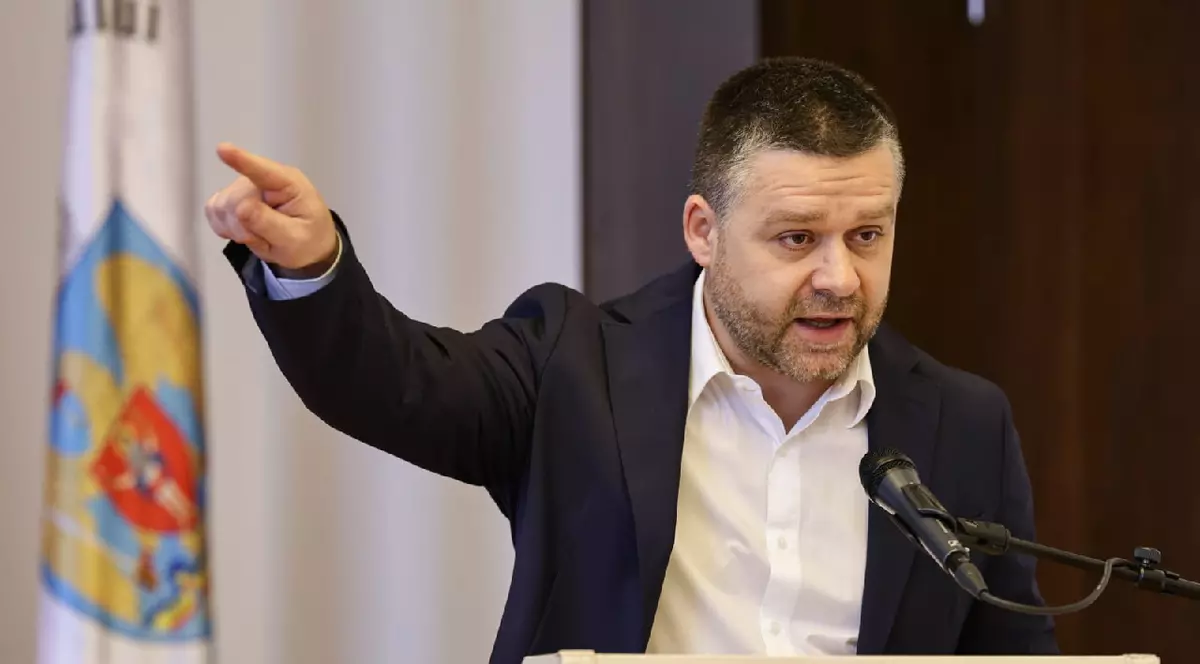 Ciprian Ciucu, cu mânădreapta întinsă, îmbrăcat în sacou negru și cămașă albă, la o conferinta de presă pe 26 martie 2026