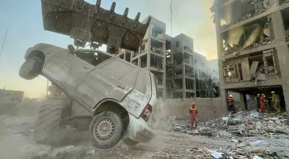 Rămășițele unei clădiri bombardate în Iran, o mașină este ridicată în prim plan.