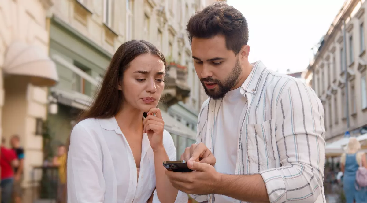 Un bărbat care îi arată lucruri pe telefon unei femei.
