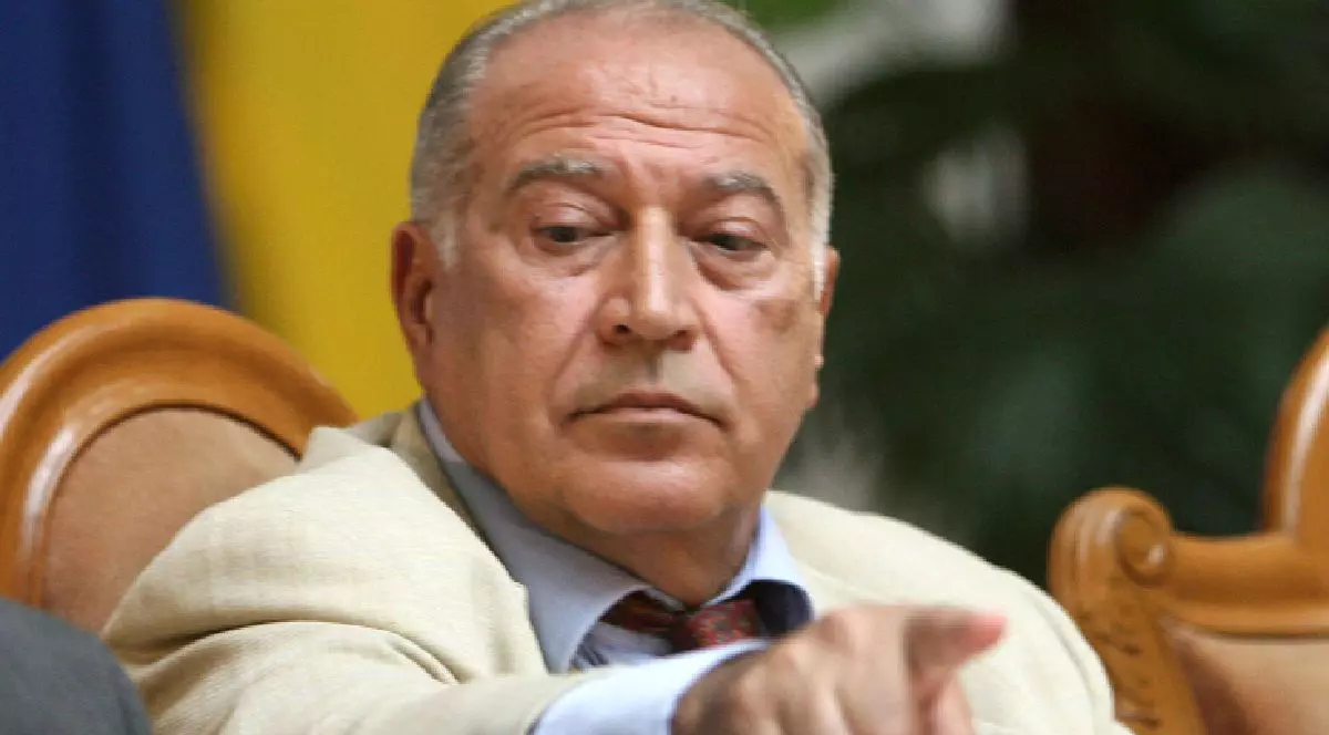 Dan Voiculescu, îmbrăcat într-un sacou de culoare deschisă (bej sau crem), purtând o cămașă bleu și o cravată cu model în nuanțe de roșu închis.