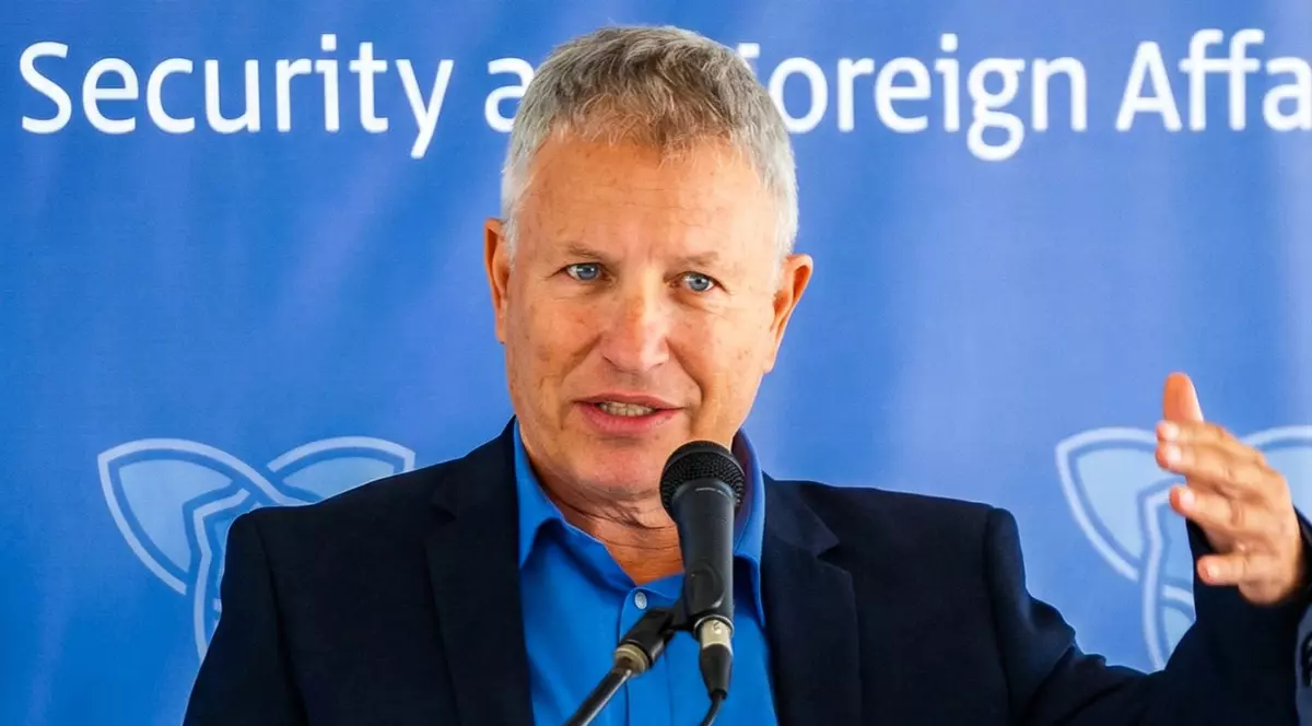 Un barbat in cosatum negru si camasa albastra vorbeste la un microfon