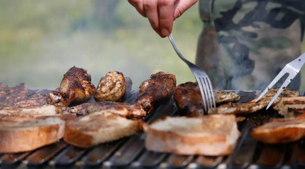 Bărbat care pregătește carne la grătar la grătar vara, în grădină