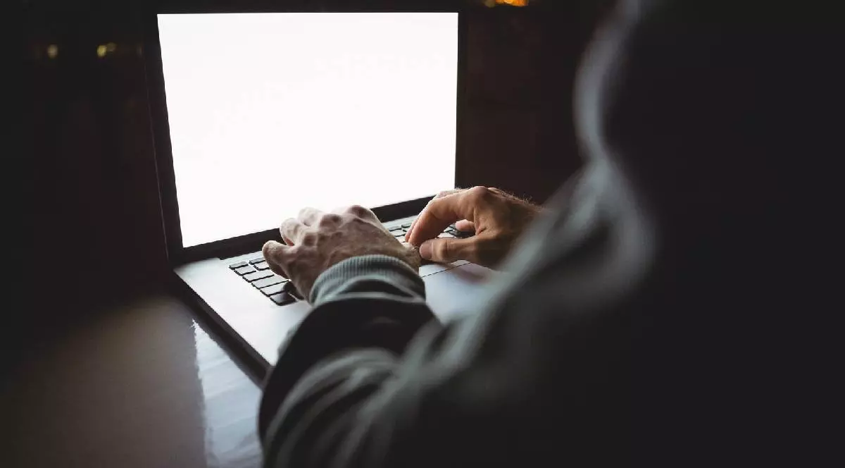 un laptop e deschis și se observă mâinile cuiva care-l manipulează