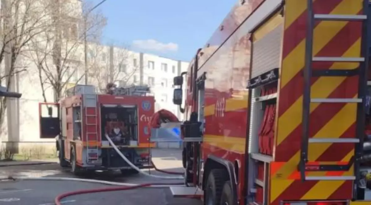 Două mașini de pompieri care intervin pentru stingerea unui incendiu dintr-un bloc