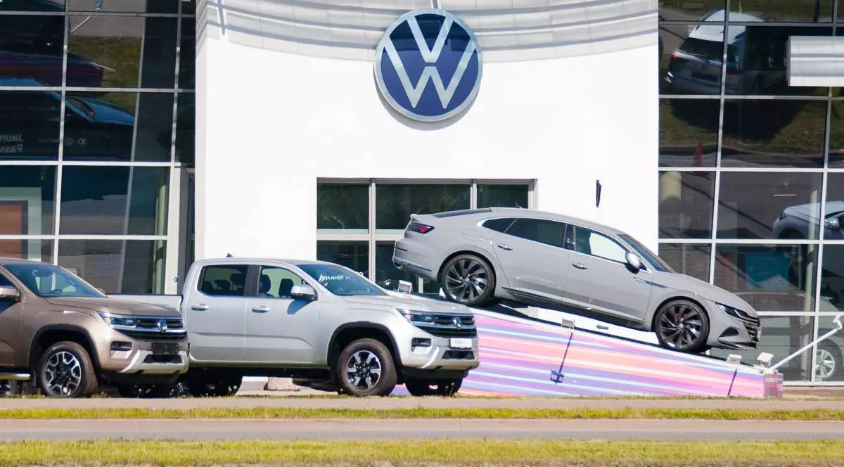 mașini Volkswagen noi, prezentate in fata fata unei clediri cu sigla VW