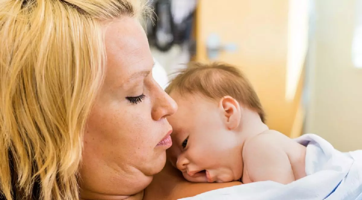 O mama sta in salon cu bebelusul la piept. Metoda Cangur, piele pe piele. Mama si nou nascut. Foto Imago