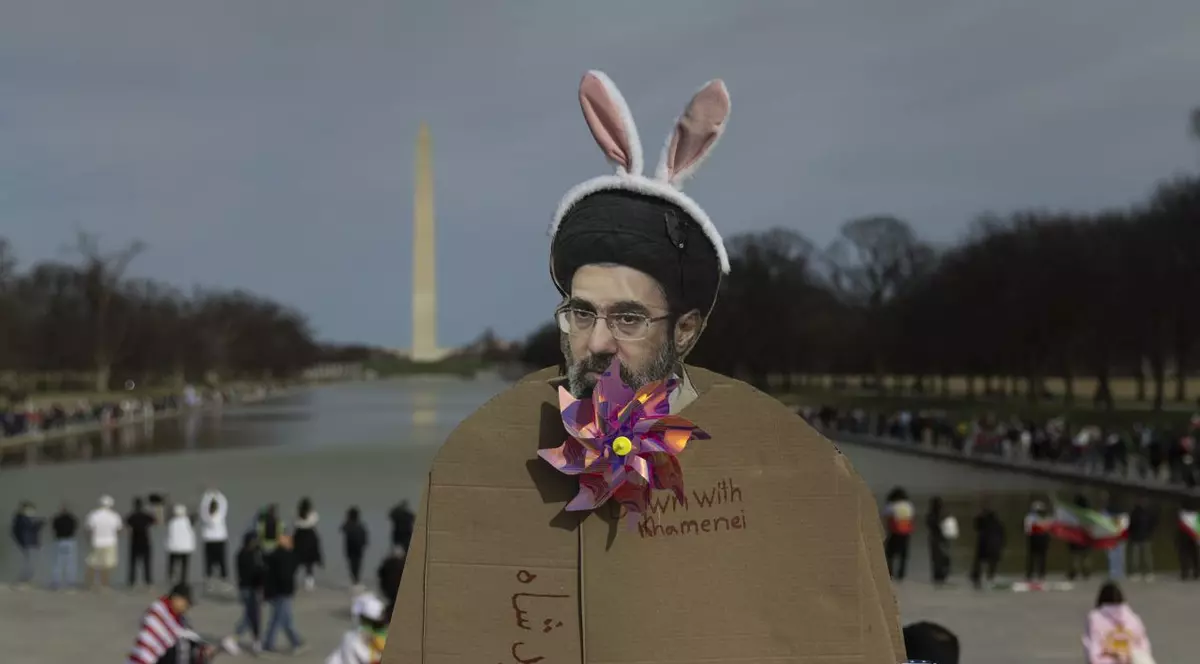 Un protestatar ține în mână o figurină de carton care îl înfățișează pe Mojtaba Khamenei purtând urechi de iepuraș în timpul unei demonstrații la Washington, pe 14 martie