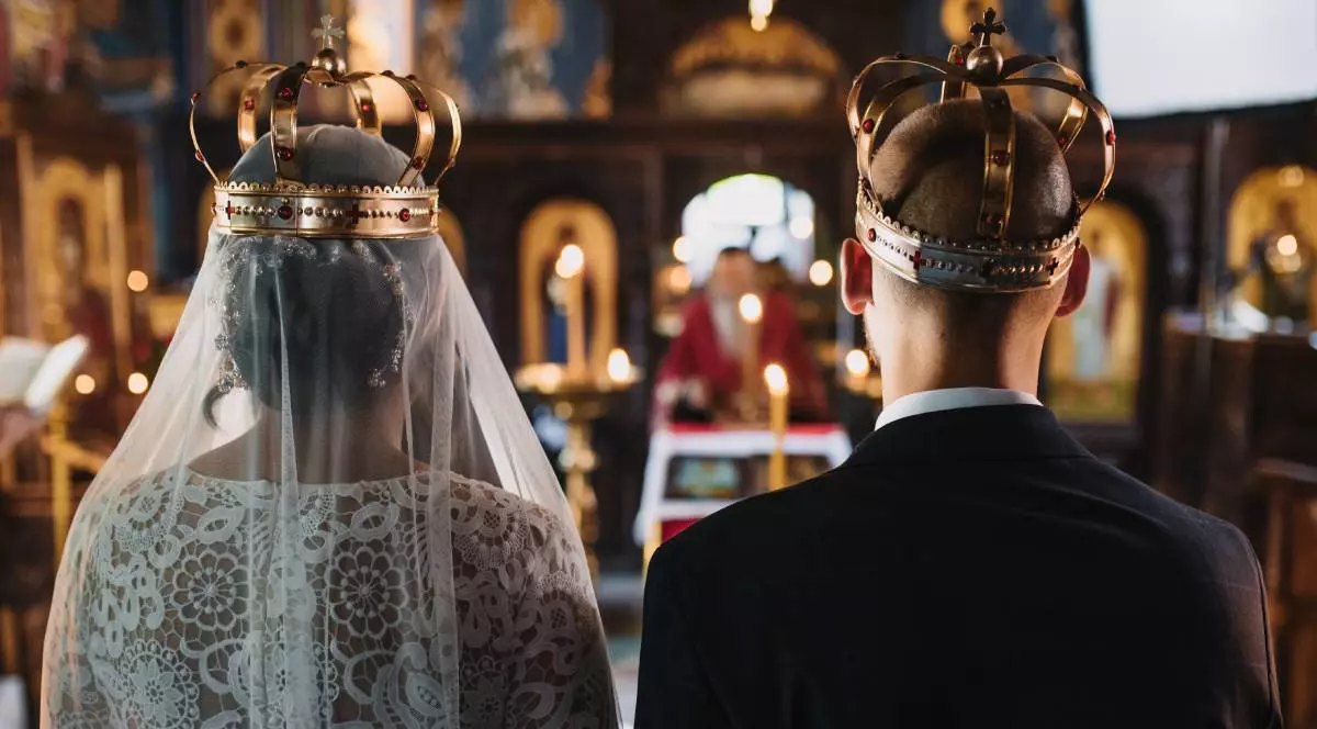 Mire și mireasă purtând coroane în timpul unei ceremonii de nuntă în biserică