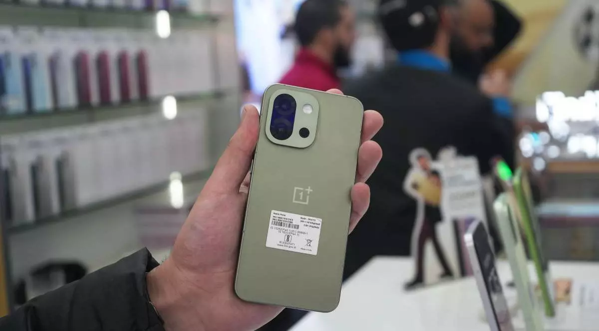 Un smartphone OnePlus 15, ținut în mână de un bărbat, într-un magazin din India.