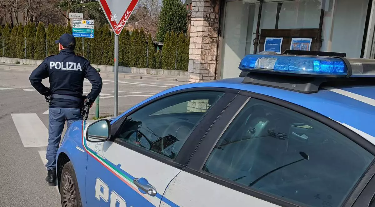 Masina de politie in strada in Italia, in fata se vede un politist cu mainile in solduri, e o zi insorita