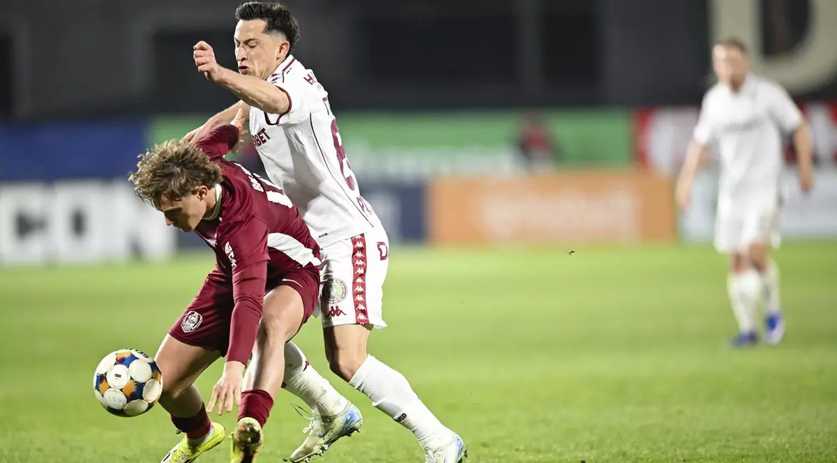 Gemini a spus Imaginea surprinde un duel intens între doi jucători în timpul meciului dintre CFR 1907 Cluj și Rapid București, disputat pe stadionul „Dr. Constantin Rădulescu”. În prim-plan, un jucător al gazdelor (CFR Cluj), echipat în echipamentul vișiniu tradițional, se află într-o luptă strânsă pentru posesia balonului cu un adversar de la Rapid, care poartă echipamentul alb. Dinamică fazei este evidentă prin postura sportivilor: jucătorul de la CFR este aplecat, încercând să protejeze mingea sub presiunea fizică a rapidistului, care îl talonează îndeaproape.