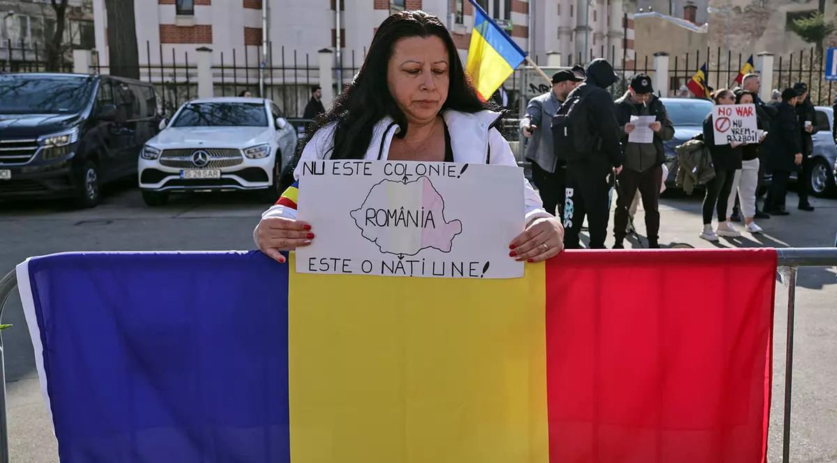 O femeie protesteaza cu un steag al Romaniei si o pancarta