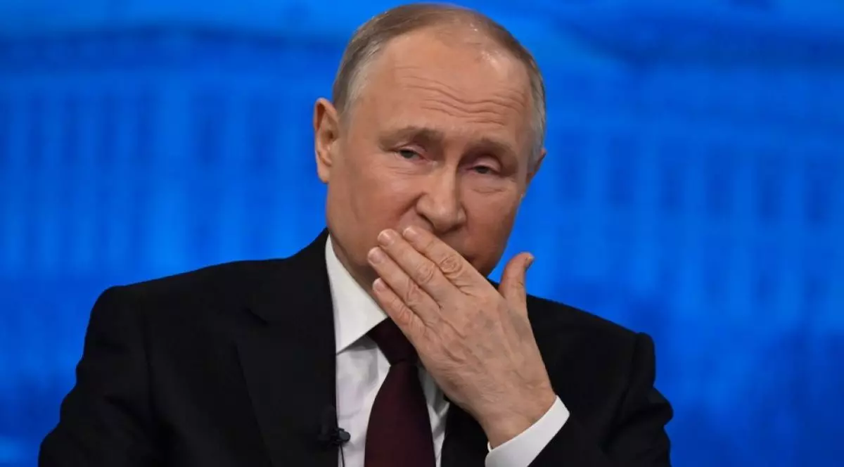Vladimir Putin, îmbrăcat în costum negru, cu cămașă albă și cravată albastră, cu mâna la gură, pe fundal de culoare albastră