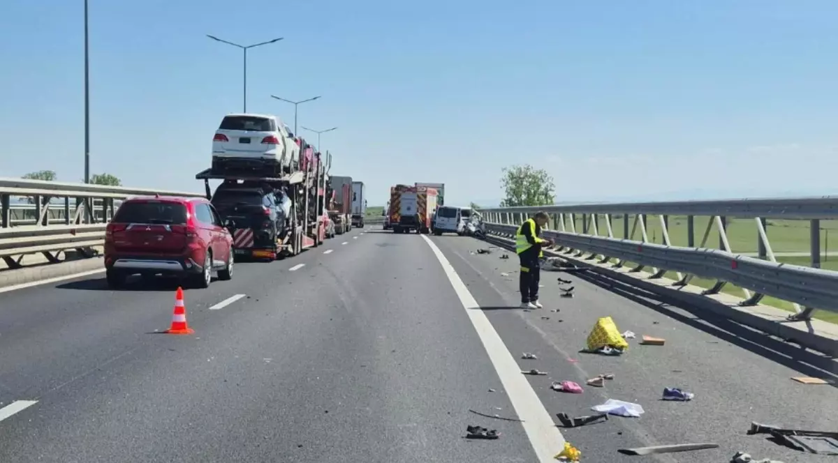 Locul unui accident rutier pe o autostradă, unde resturi de vehicule și obiecte personale sunt împrăștiate pe carosabil lângă un parapet metalic. În plan îndepărtat, o autospecială de pompieri și un vehicul avariat blochează drumul.