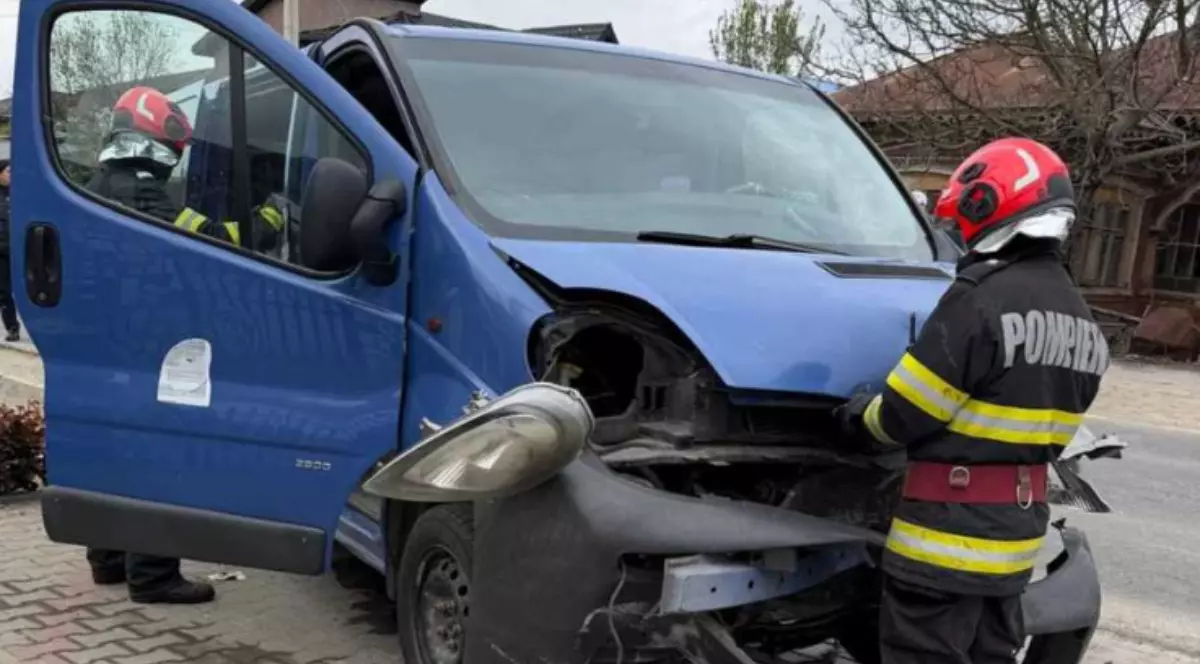 Pompieri care se află lângă un microbuz albastru, în urma unui accident.