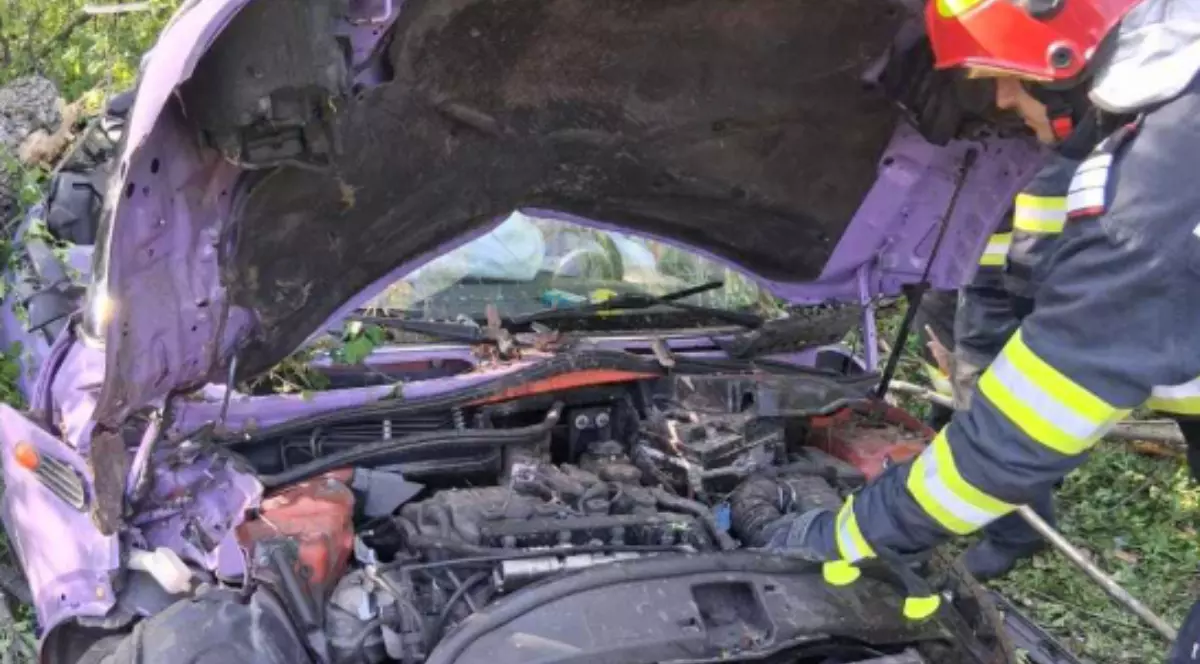 Un pompier lângă o mașină avariată în urma unui accident