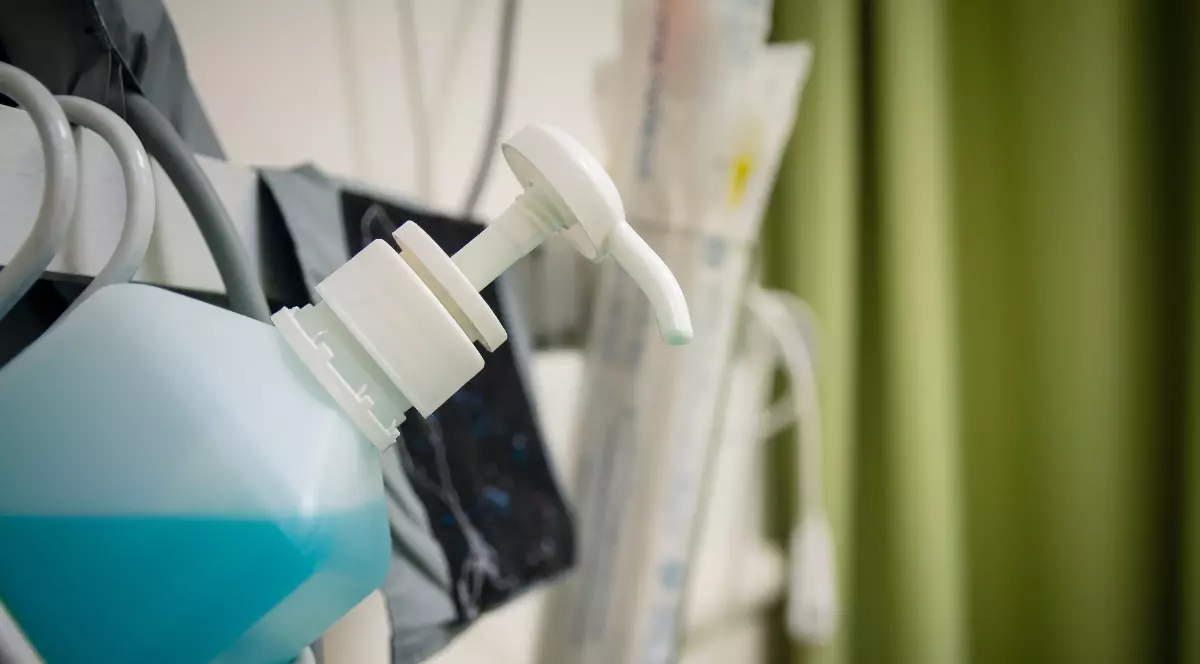 Imaginea ilustrează un recipient cu antiseptic într-un cadru medical de spital