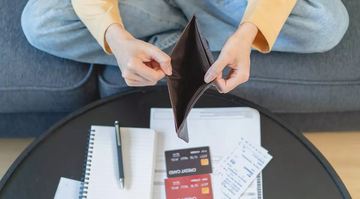 tanara studenta cu portofelul gol in fata unui teanc de documente si facturi