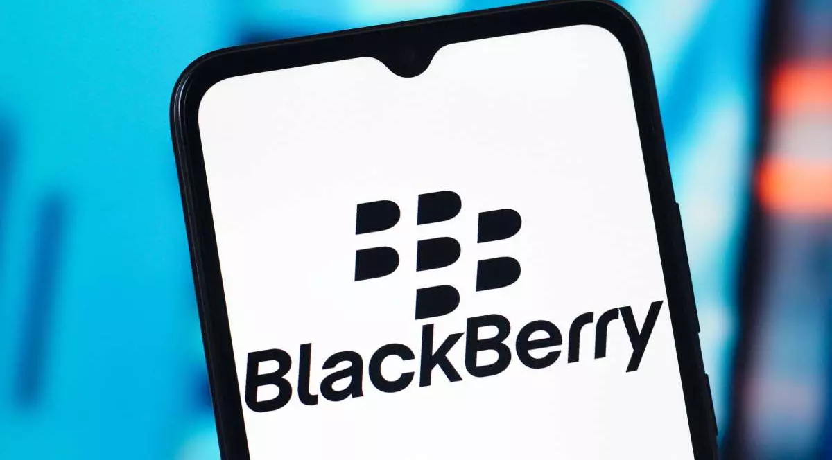 Logo-ul BlackBerry afișat pe ecranul alb al unui smartphone generic, în fața unui fundal albastru deschis.