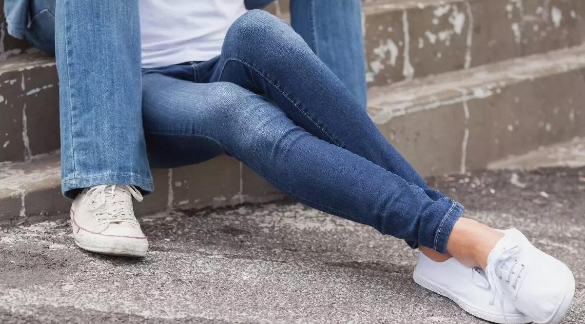 un el și o ea îmbrăcați cu pantaloni din denim stau pe niște trepte