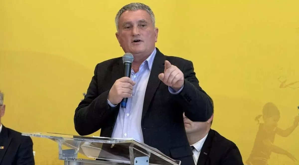 Deputatul PNL Cristian Buican vorbește la micrfon la o conferință de presă și arată cu degetul, imaginea este pe un fundal galben