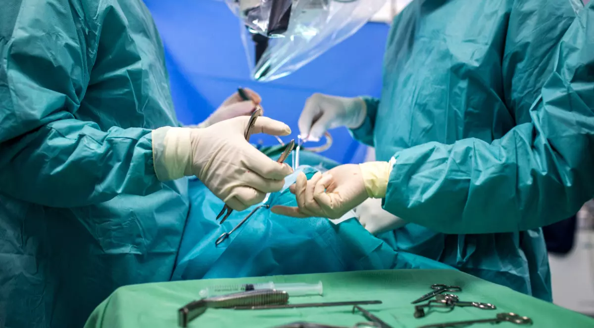 Doi medici care efectuează o operație, în sala de operație, au pe tavă toate instrumentele necesare sterilizate