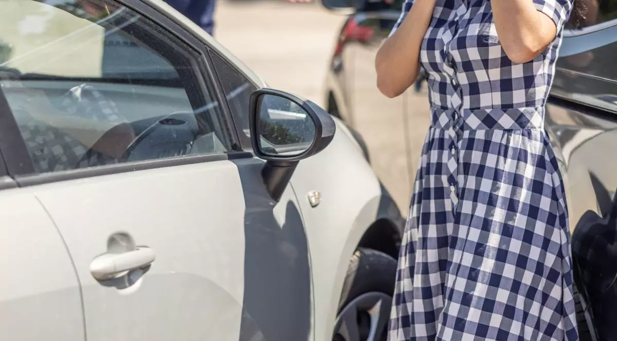 silueta femeie in rochie in carouri alb / negru, in strada, langa o masina gri