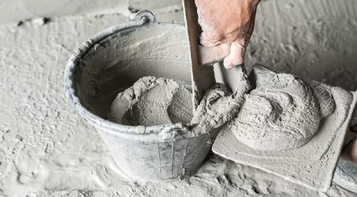 Care este diferenţa dintre ciment, beton şi mortar - Imagine cu un zidar care ia mortar dintr-o găleată