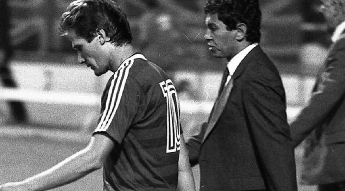 Ladislau Boloni și Mircea Lucescu pe terenul de fotbal, într-o fotografie alb negru. Ladislau Boloni poartă echipamentul naționalei României, iar Mircea Lucescu este îmbrăcat la costum