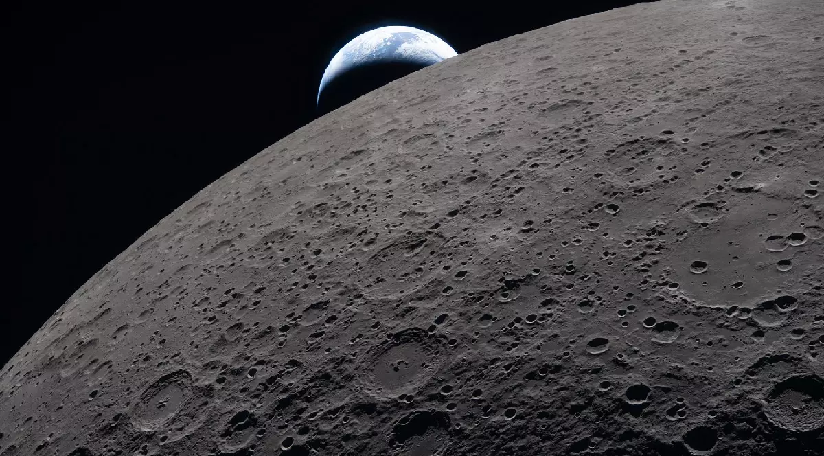 Suprafața lunară umple cadrul cu detalii clare, așa cum se vede în timpul survolului lunar al navei Artemis II, în timp ce se vede și un Pământ îndepărtat