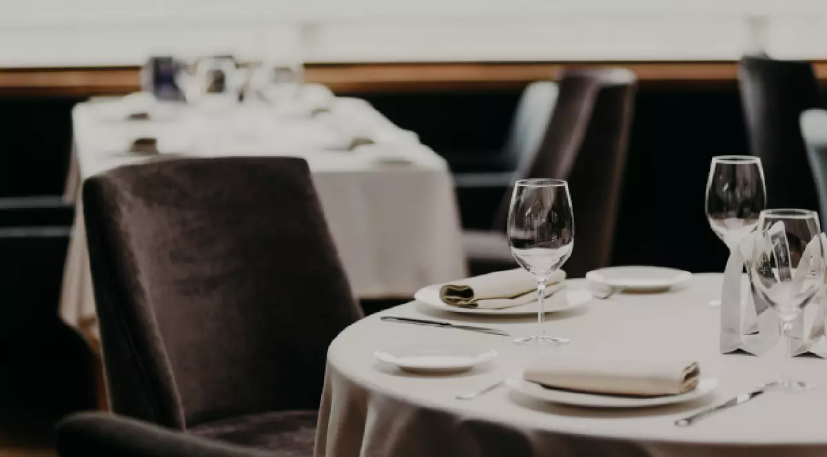 O masă dintr-un restaurant cu tacâmuri, farfurii și pahare