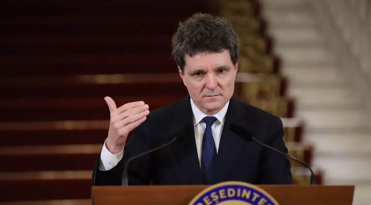 Nicușor Dan, îmbrăcat într-un costum bleumarin, cămașă albă și cravata vorbește de la pupitrul prezidențial.