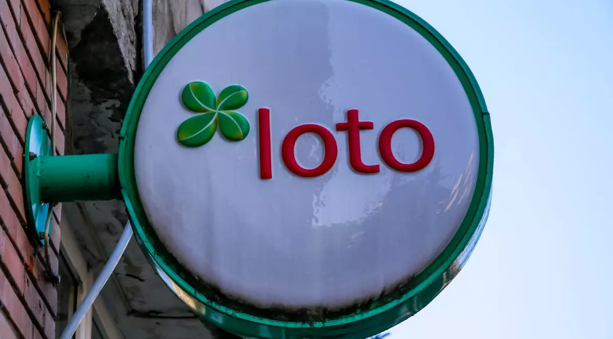 Panou stradal pe care scrie Loto, afișat lângă o agenție a Loteriei Române, pe peretele unui bloc