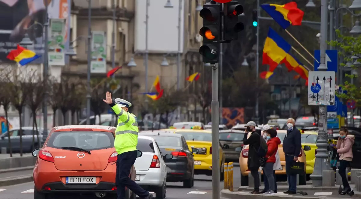 București, România – 28 aprilie 2021: Un polițist dirijează traficul la o intersecție din București.