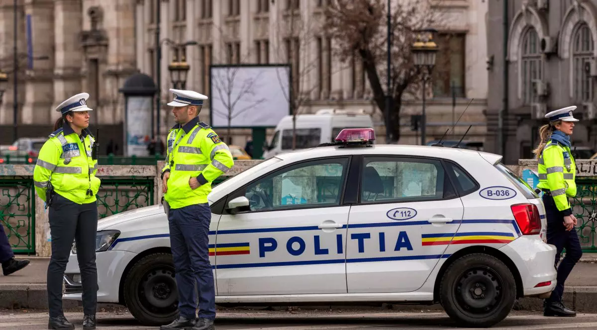 Polițiști de la Rutieră, îmbrăcați în uniforme, lângă o mașină de Poliție Volkswagen Polo, iar pe fundal clădiri din București